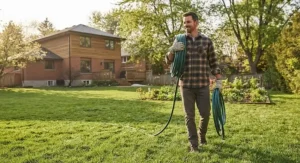 A Canadian homeowner easily carrying a lightweight garden hose that doesn't kink across a large lawn.